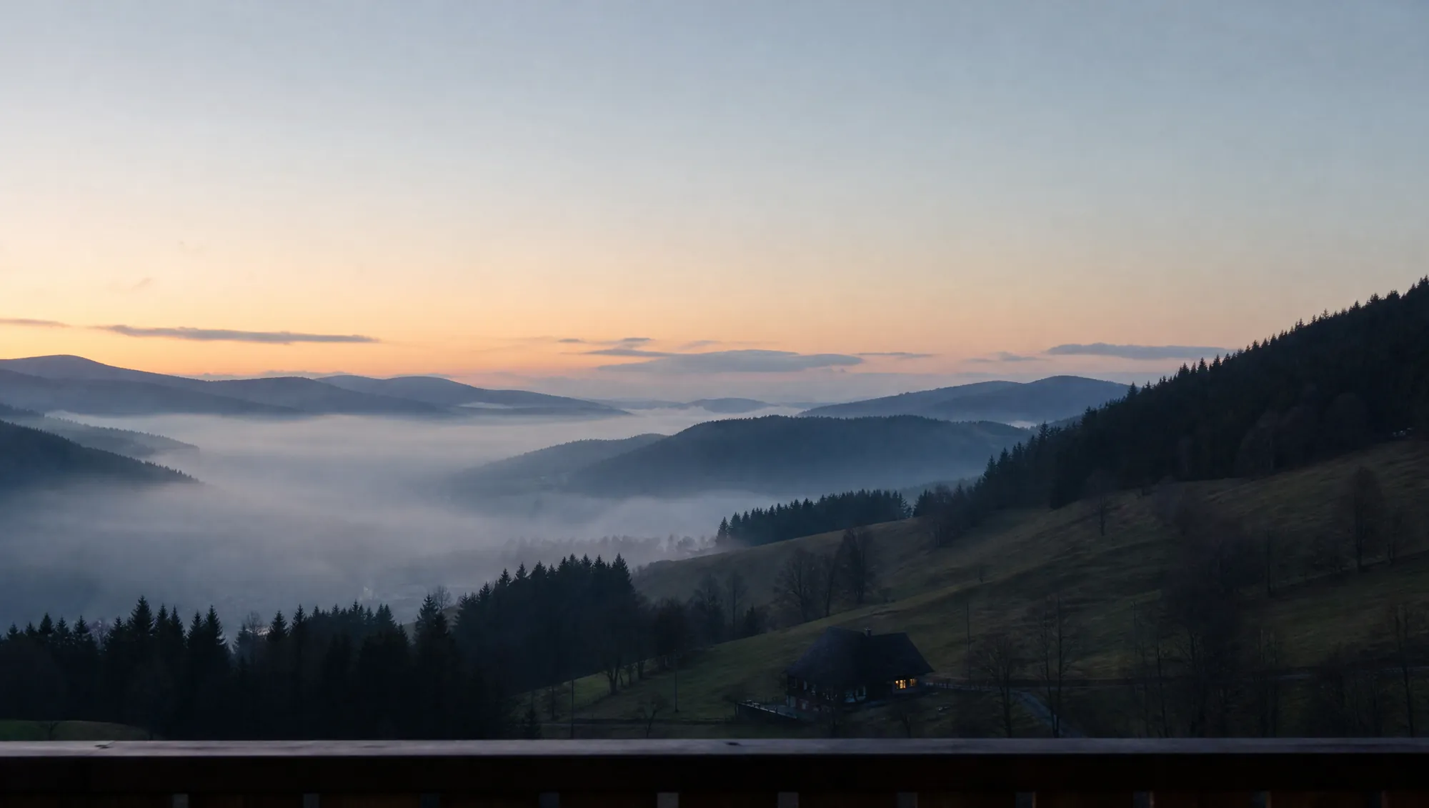 Morgennebel im Tal unterhalb des Gasthofs, ein erleuchtetes Fenster in einem Hof am Hang